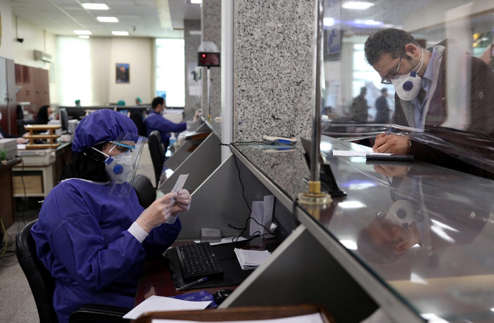 Iran: An employee and client, with masks at a bank, in Tehran because the outbreak of coronavirus - March 2020