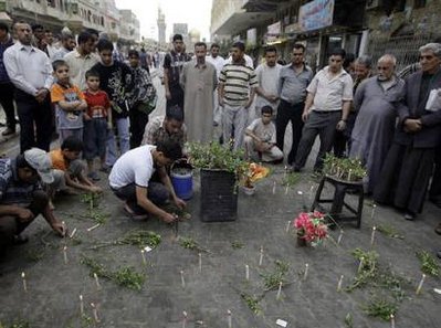 Residents light candles at the site of a bomb attack in Baghdad's Kadhimiya district April 24, 2009. 